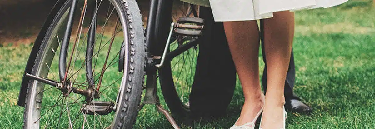 Füße in weißen Sandalen vor einem Fahrrad auf einer grünen Wiese